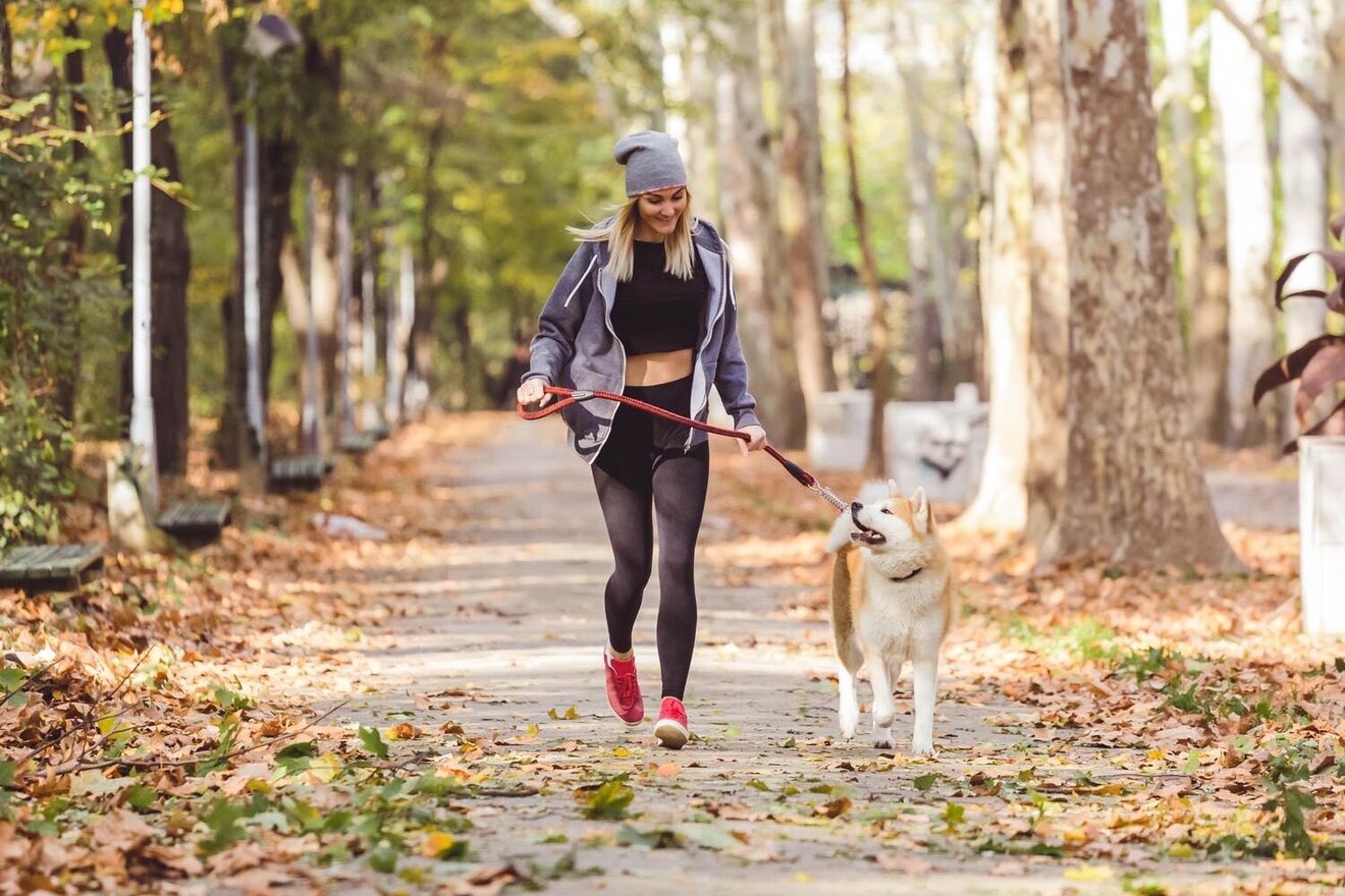 Eine Frau joggt mit ihrem Hund im Wald